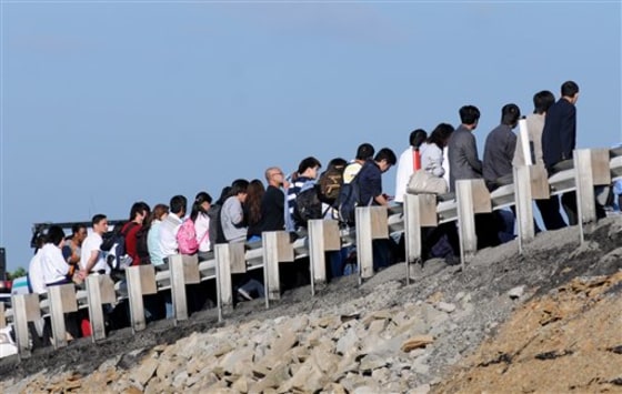 Tour bus passengers line up along the guard rail Monday while they wait to be transported from the scene of a bus accident along the eastbound lane of the Pennsylvania Turnpike.